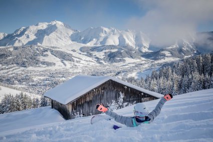 Snowboarder sitting in deep snow with chalet and mountain view - Snow-wise - Our complete guide to Megève, France - Megève's snow record