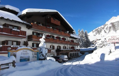 Exterior view of the snow-covered chalet-style 4 star Hotel Evaldo in the ski resort of Arabba, Italy