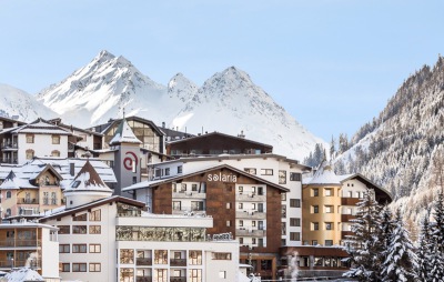 Winter view of the exterior of the 4 star superior Hotel Solaria and the ski resort of Ischgl, Austria, with snow-covered mountains in the distance