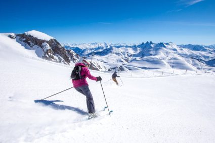 Skiers enjoying the slopes of Alpe d'Huez, France, with panoramic views across the French Alps