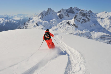 Skier in fresh snow in Lech-Zürs, Austria, with snow-covered mountains in the background