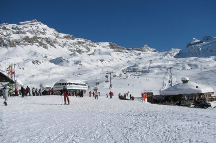 Skiers on snow-covered pistes at Plan Maison above Cervinia, with chairlifts and Alpine mountains in the background